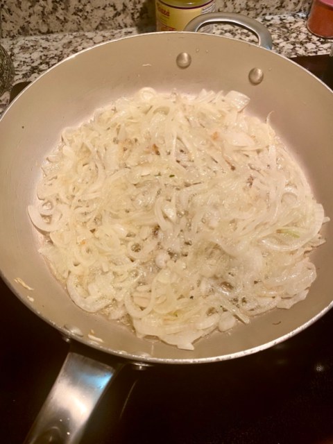 white onions frying in a pan full of ghee, they're still white but bubbling