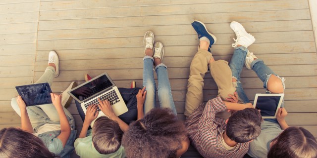 students sit on the floor with laptops