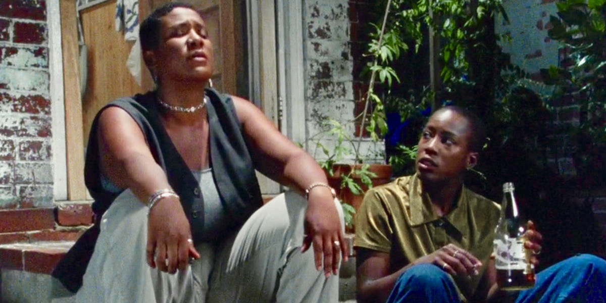 A still from Cheryle Dunye's The Watermelon Woman. Two black queer women sit on a stoop at night, talking with each other.