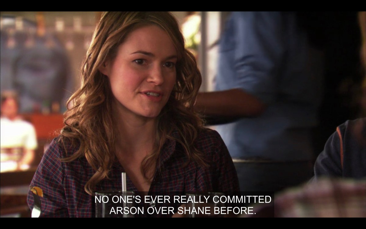 Alice wearing a plaid shirt sitting at the Planet saying "No one's ever committed Arson over Shane before"
