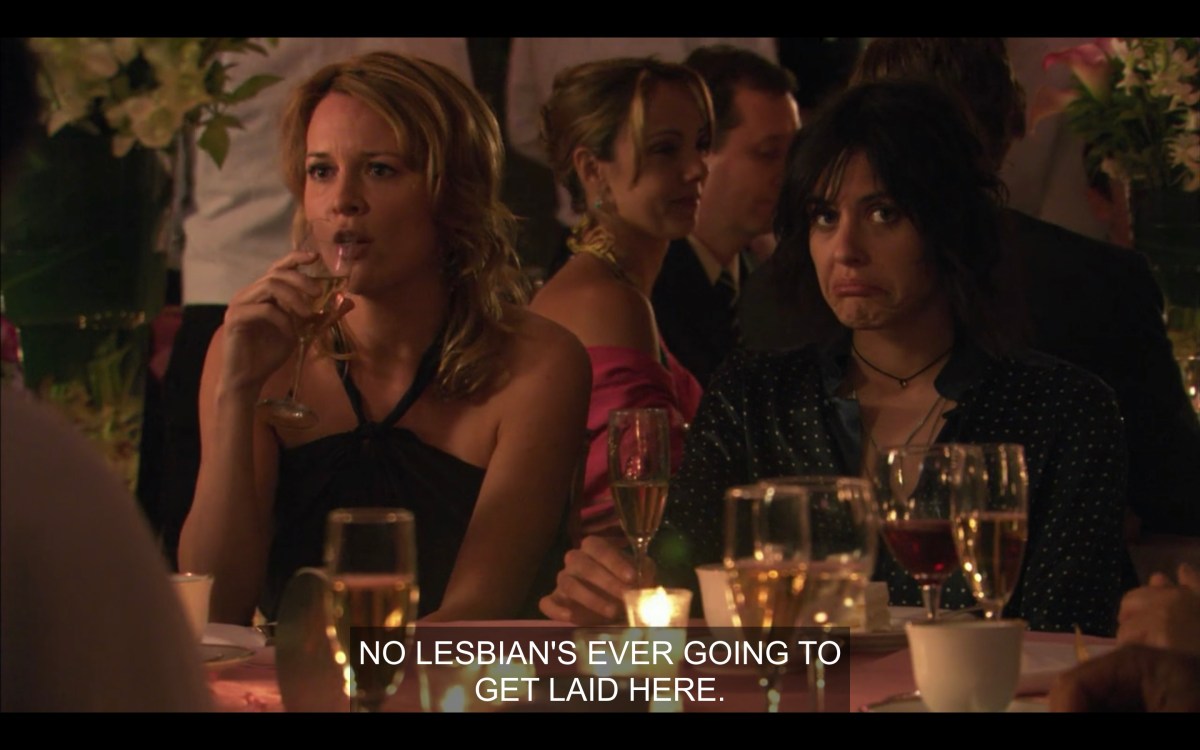 Sitting at a table at the wedding, Tina drinking wine saying "No Lesbian's ever gonna get laid here." Next to her, Shane's face is like "are you sure?"