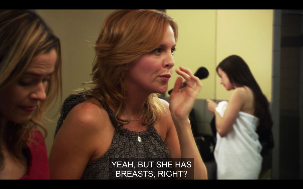 Tina and Alice doing their makeup. Tina says, "yeah, but she has breasts, right?"