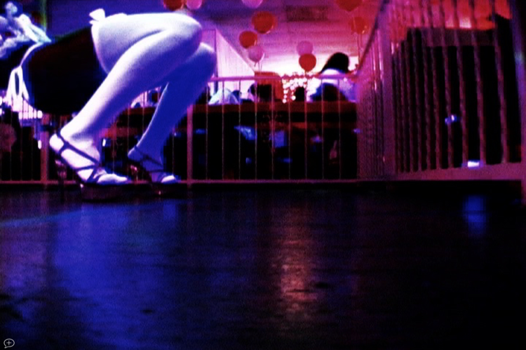 a shot of the empty dance floor of a party where one person in heels is dropping it low