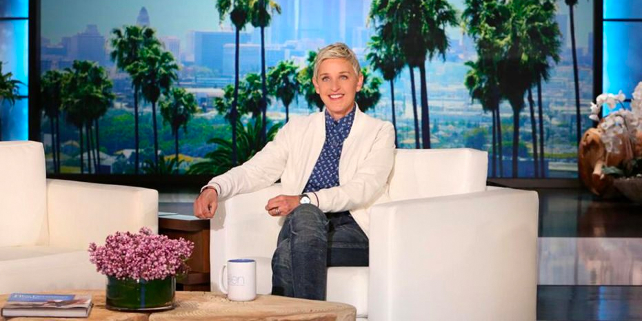 Ellen Degeneres on the set of her talks show, seated and smiling at the camera.