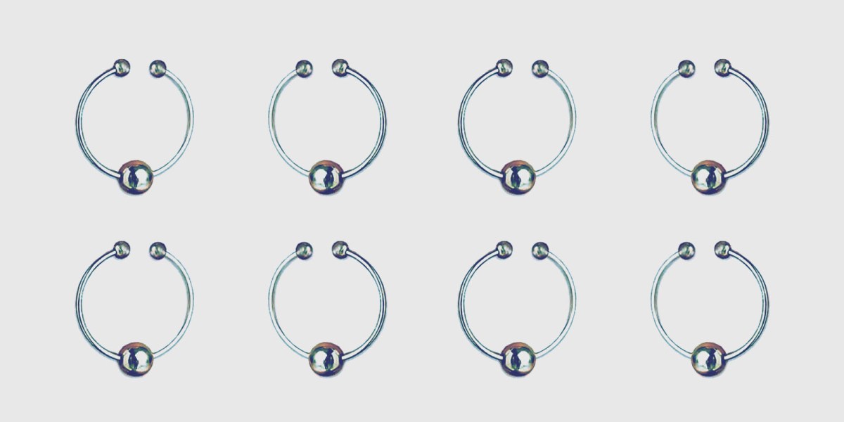 An array of small stainless steel nipple rings with an opening in ring to be worn or removed, and a single steel ball dangling on the hooped ring