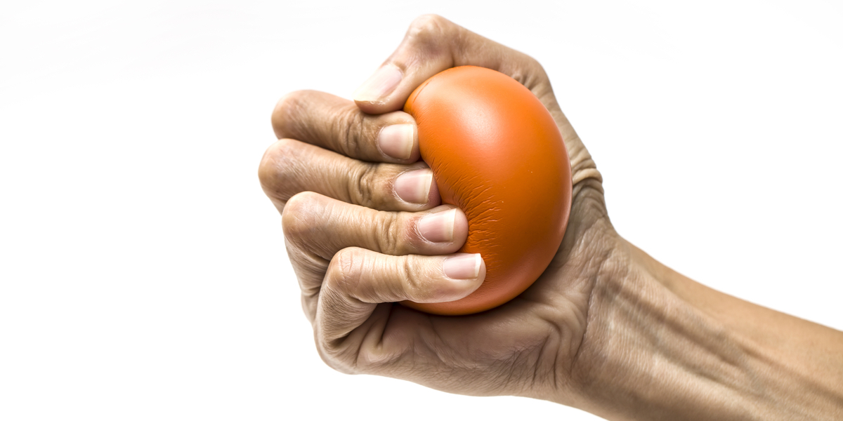 a hand grips an orange stress ball