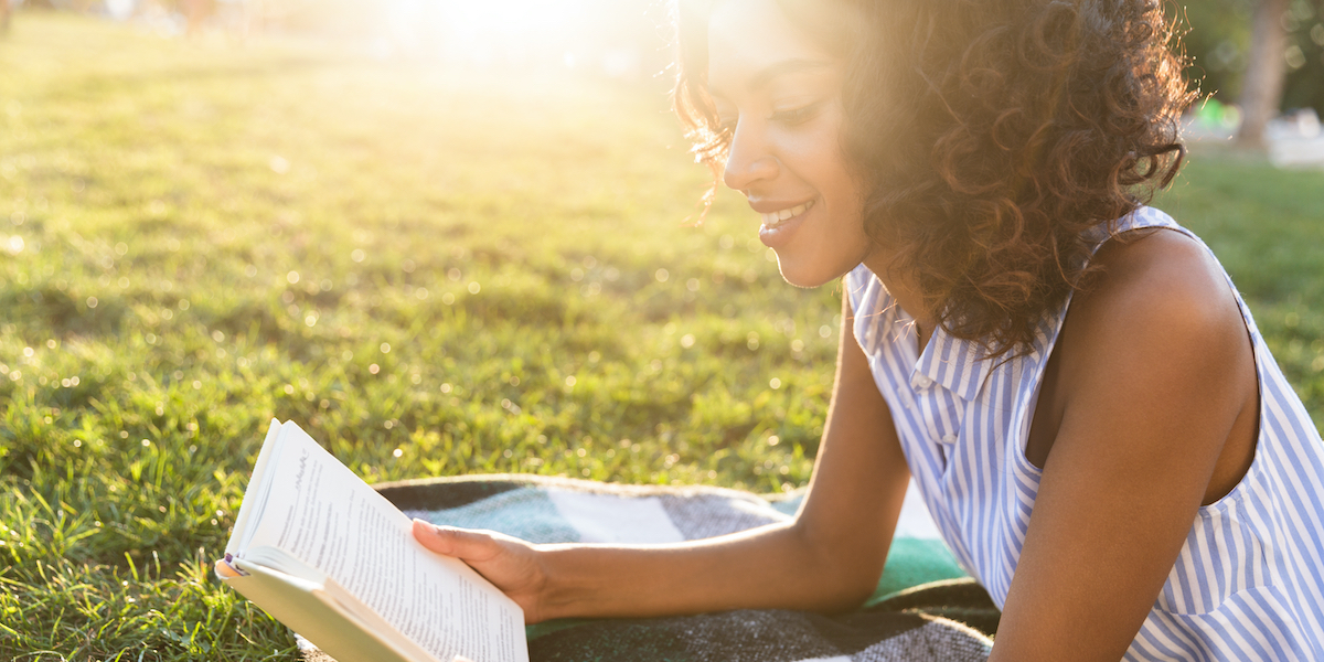 a woman reading on the grass at golden hour