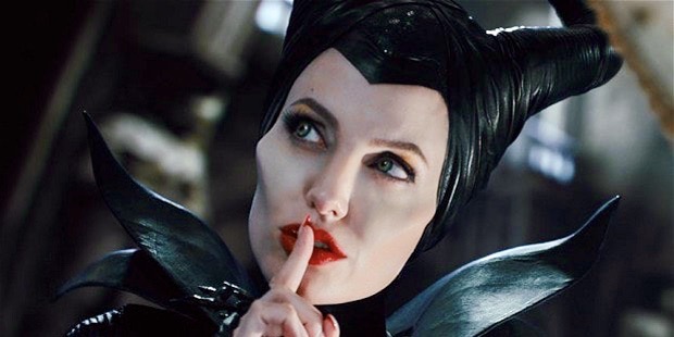 A still of Angelina Jolie from the movie "Maleficent." She is holding her finger to her mouth, as if to say "shhhhh" because she knows the reason that snakes don't need men for anything.