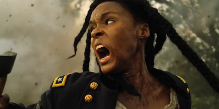 Janelle Monáe in "Antebellum" as the character Eden. Eden screams in anger, her face in profile to the camera, as smoke from torches fill the screen behind her.