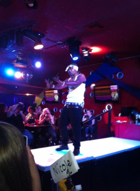 the author in a white tank top and jeans with a white dorag tied at the front of his forehead, performing in drag as Tupac
