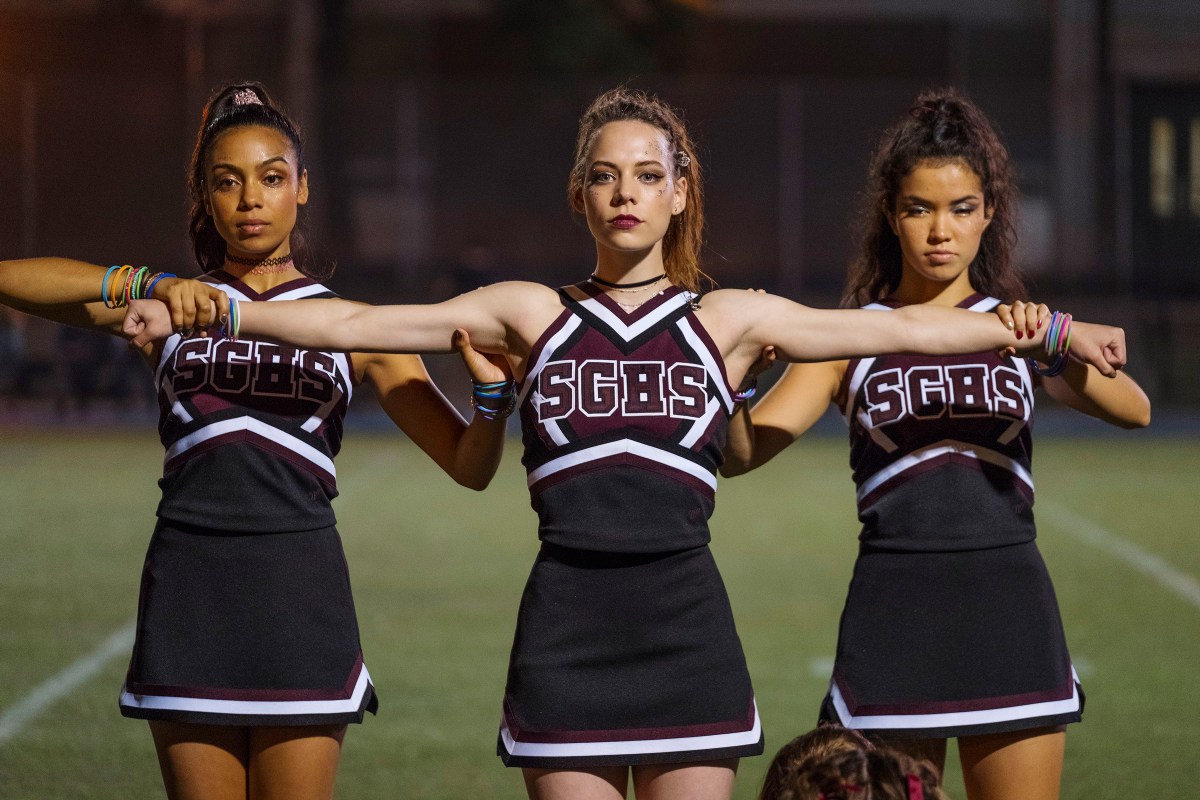 three cheerleaders on the field with their arms out. a still from "dare me"
