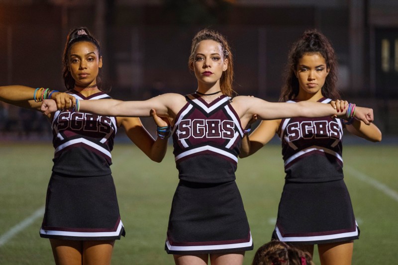 Dare Me is a show like Yellowjackets. Three cheerleaders on the field with their arms out. a still from "dare me"