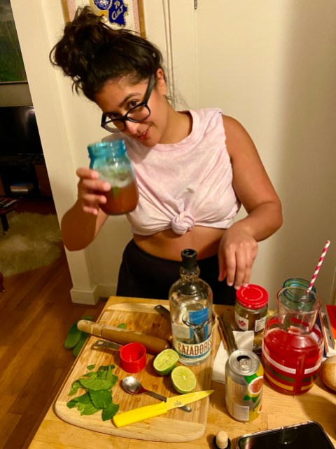 sarah raises a blue glass jar for a toast, with a pink watermelon cocktail inside