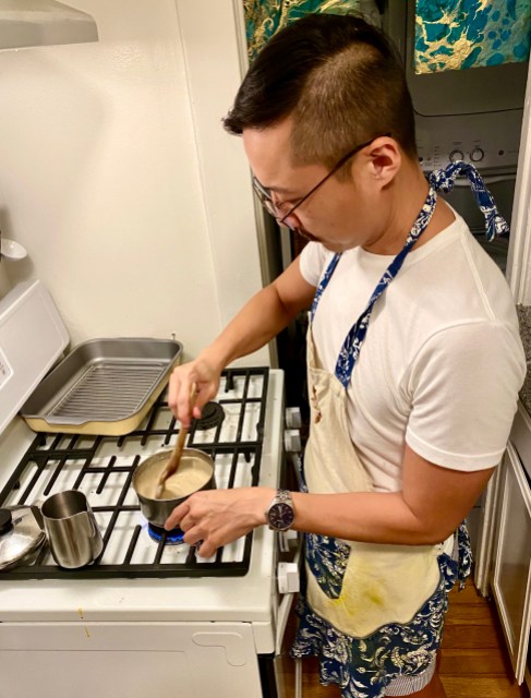 Vinh;Paul in a cute apron with floral frills, stirring a pot of gravy