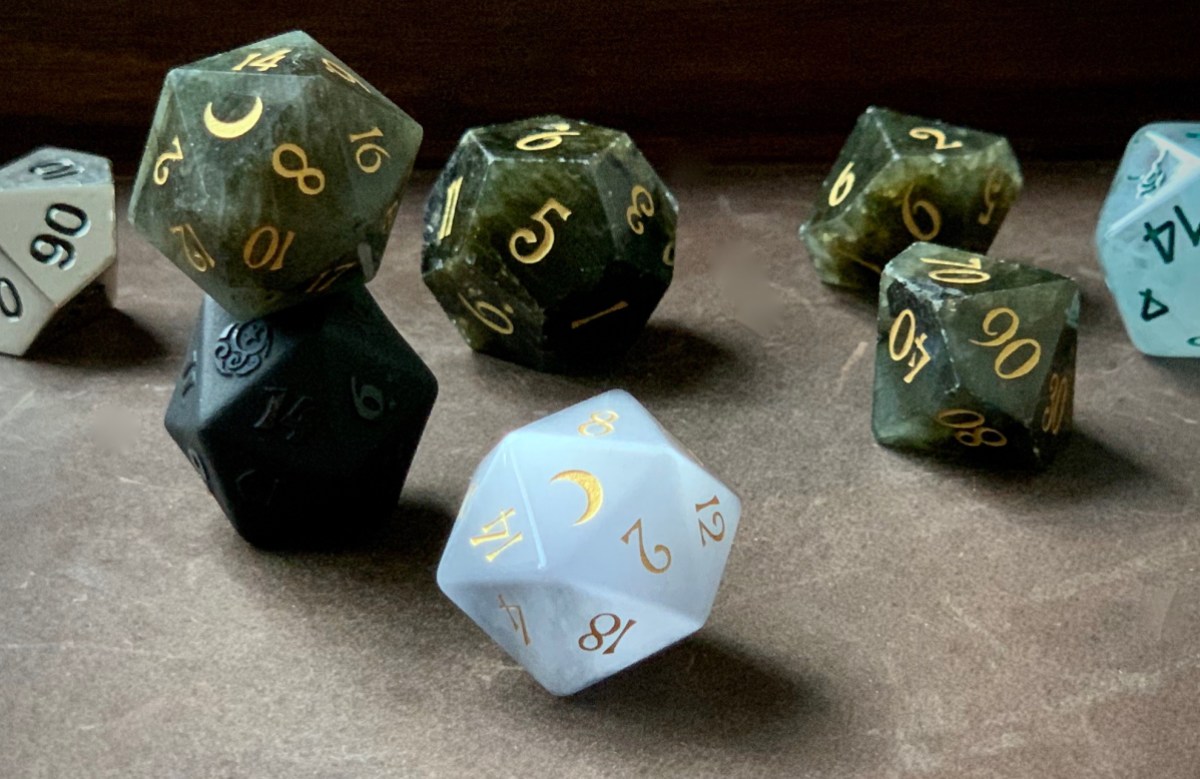 A composed photo of a beautiful set of Dungeons & Dragons dice, in a range of colors and materials from deep green cloudy gemstone with gold lettering to opaque matte black to cloudy quartzlike white to silver metal.