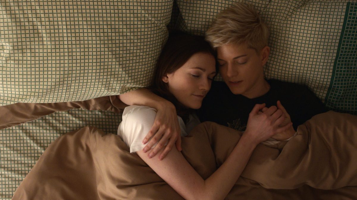 Mae in bed with her girlfriend in "Feel Good"