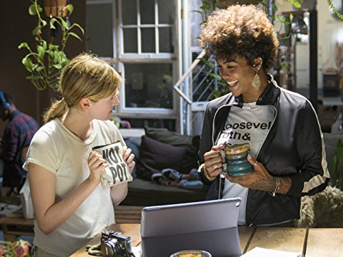 Two women stand with mugs in front of a laptop in a loft apartment with a lot of plants in it. They are both smiling. It's from the show "High Maintenance"