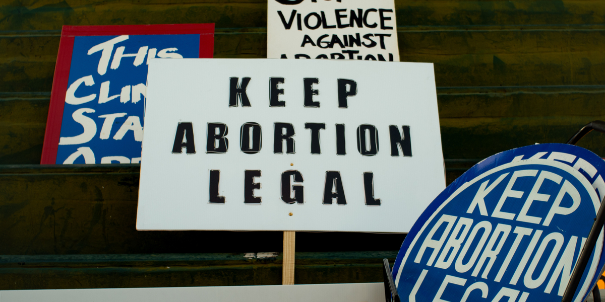 A range of pro-choice protest signs, the central one reading KEEP ABORTION LEGAL