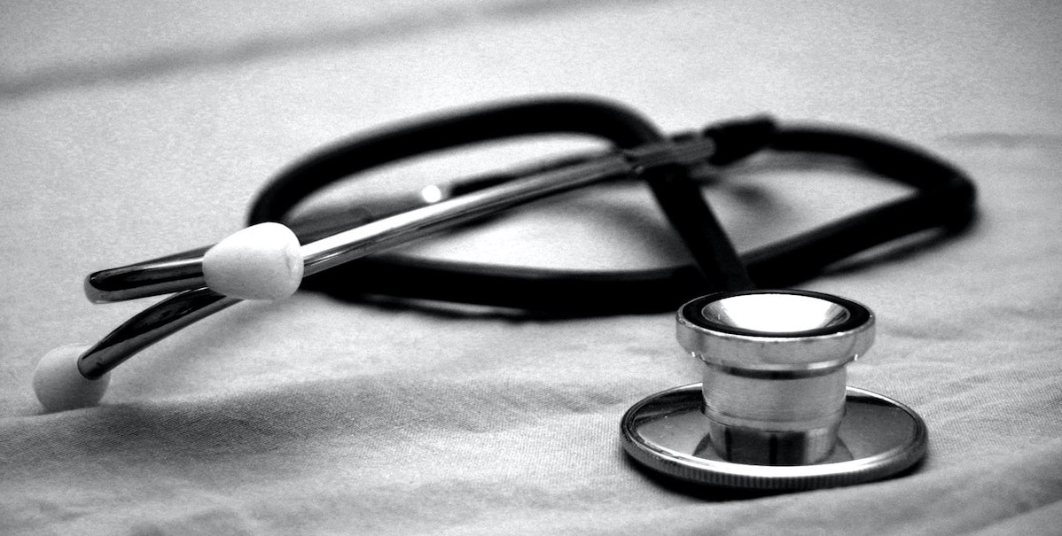 a black and white photo of a stethoscope, curled up, on top of a piece of fabric