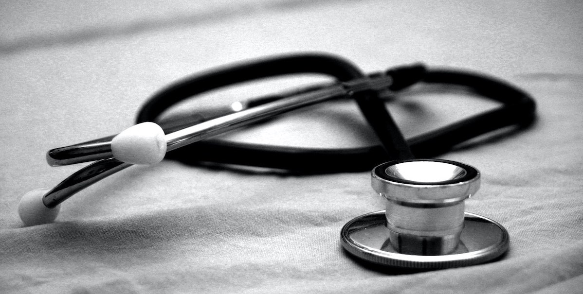 a black and white photo of a stethoscope, curled up, on top of a piece of fabric