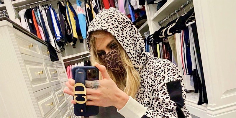 Cara Delevingne takes a selfie in her oversized closet. She's wearing a leopard print hoodie with a leopard print mask.