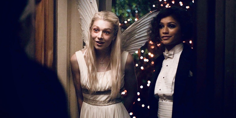 A photo still of the television series "Euphoria" in which Rue and Jules are dressed up as Romeo & Juliet. The lights sparkle behind them.