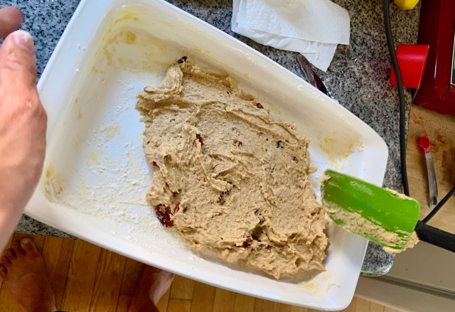 my mom's casserole pan with a plop of blondie batter in the bottom, getting spread out by a spatula