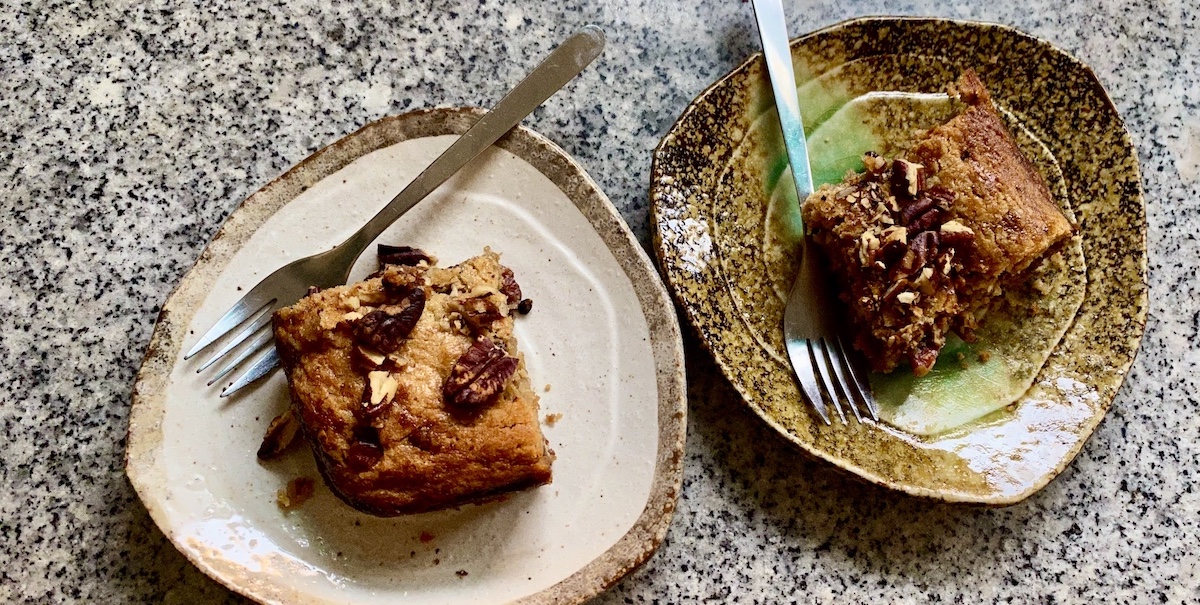 two ceramic plates with rectangles of pecan-covered blondie bars, with small forks sticking off of the sides.