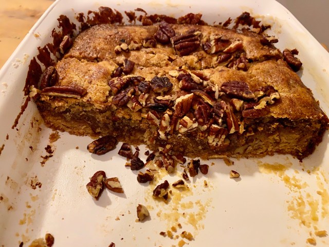 a half-eaten pan of blondies with a pile of pecans scattered on top and in the bottom of the pan