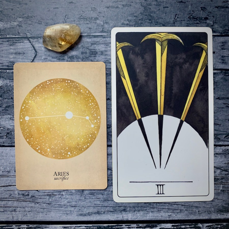 An Aries card from the Constellations tarot along with a Three of Swords
