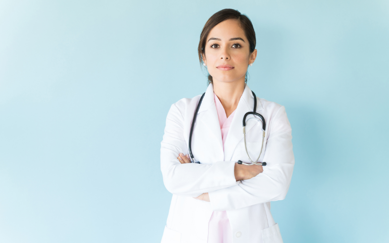 A woman in a lab coat crosses her arms.