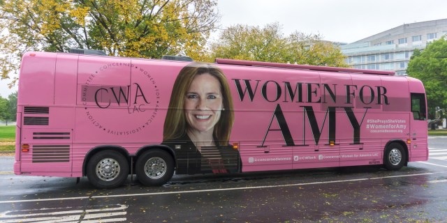 A baby pink tour bus featuring ACB's face and the text WOMEN FOR AMY