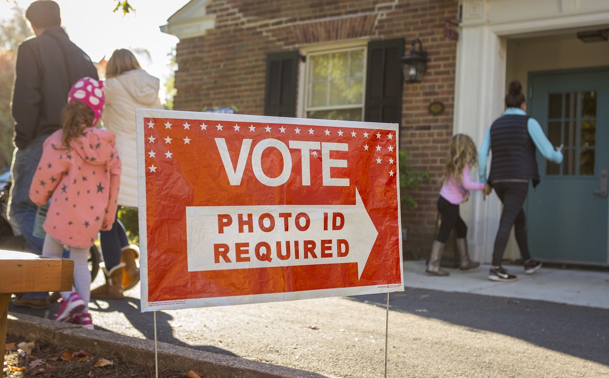 a red sign outside of a building that reads "VOTE: photo ID required"
