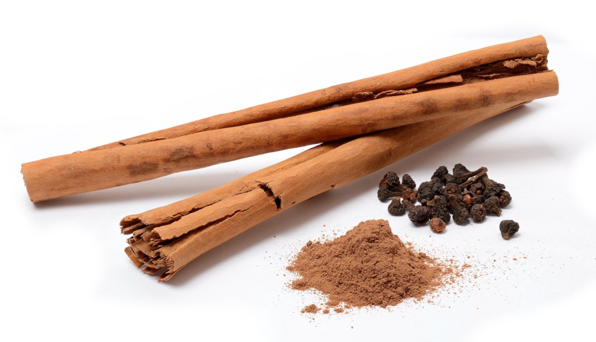 two sticks of cinnamon with a small mound of cinnamon powder