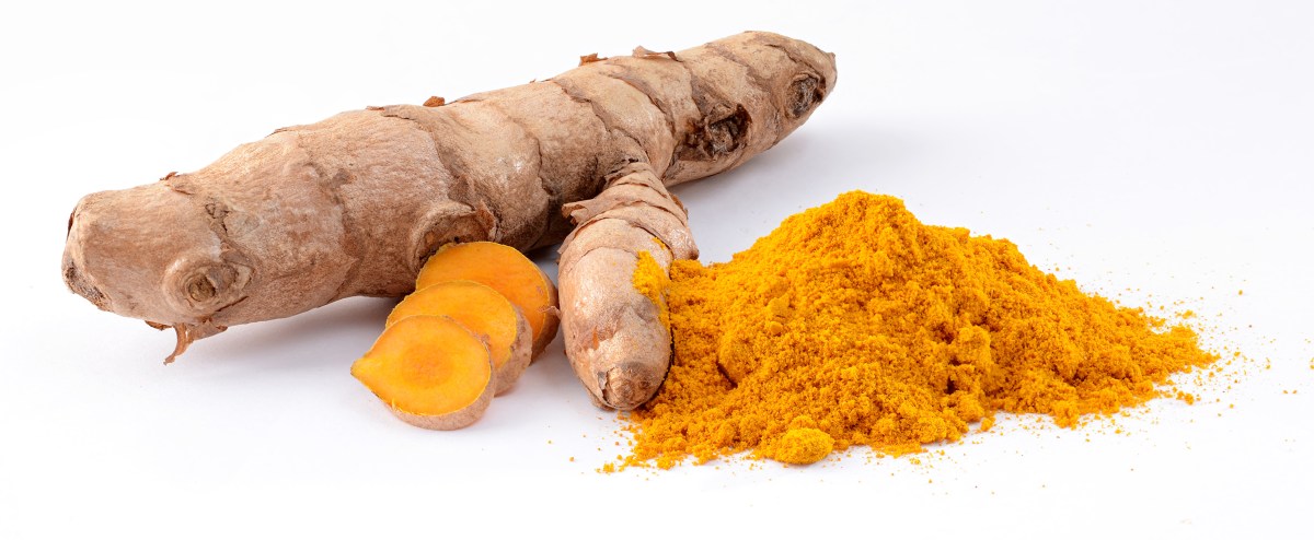 a turmeric root with some sliced pieces and a mound of turmeric powder