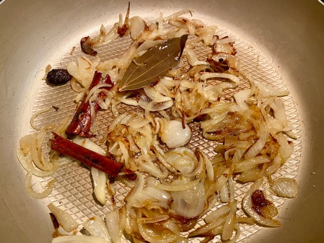 a pan full of herbs, spices and onions cooking