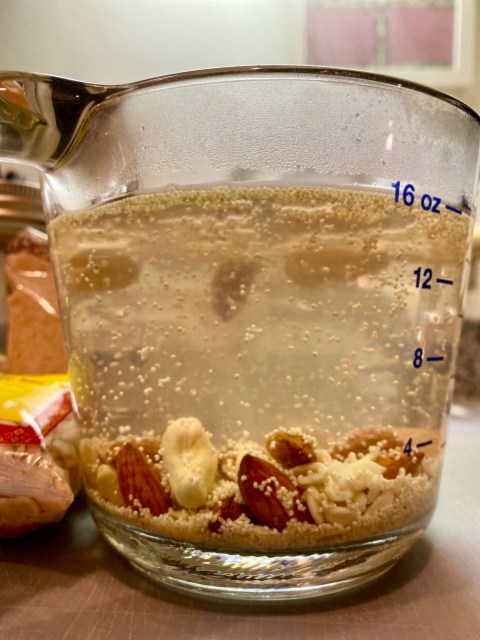 a glass measuring cup full of water with nuts and seeds floating in it