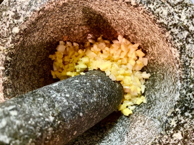 mortar and pestle with ginger and garlic getting pounded