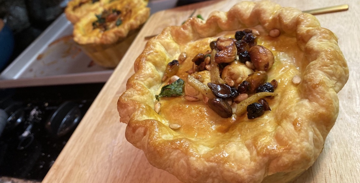 a small korma chicken pot pie that looks like a golden crown, topped with fried herbs and nuts