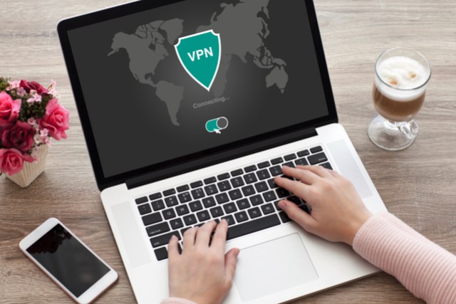 A person's hands are seen typing on a laptop that says "VPN" on the screen