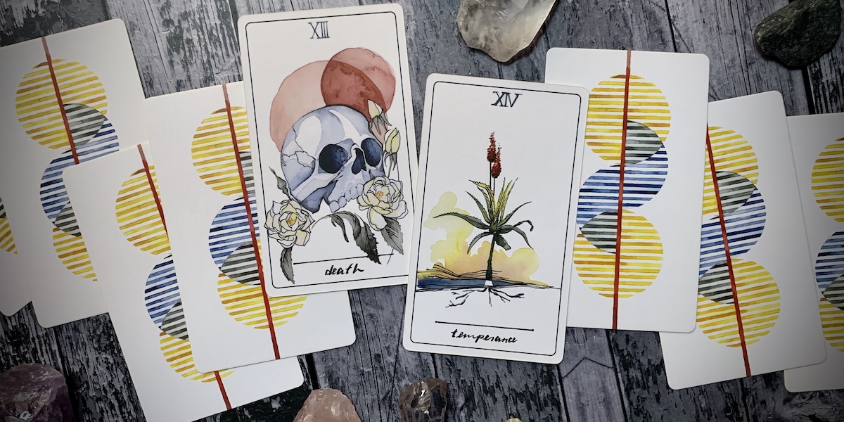 A handful of tarot cards scattered across the table, with Death and Temperance facing up