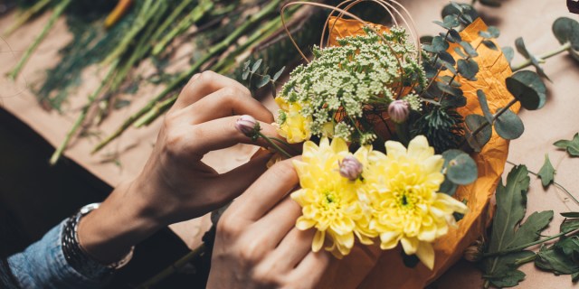 a pair of hands arranging a bouquet of flowers in closeup