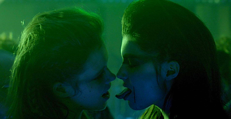 Michalina Olszanska and Marta Mazurek almost kiss in green neon lighting.