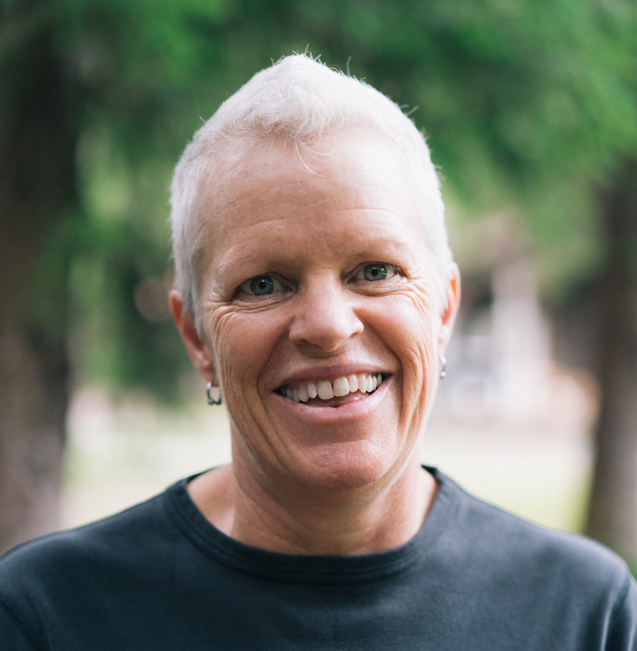 Amy Butcher, a person with a wide smile and short white hair, looking into the camera. She's a contributor to Best Lesbian Erotica Vol 5
