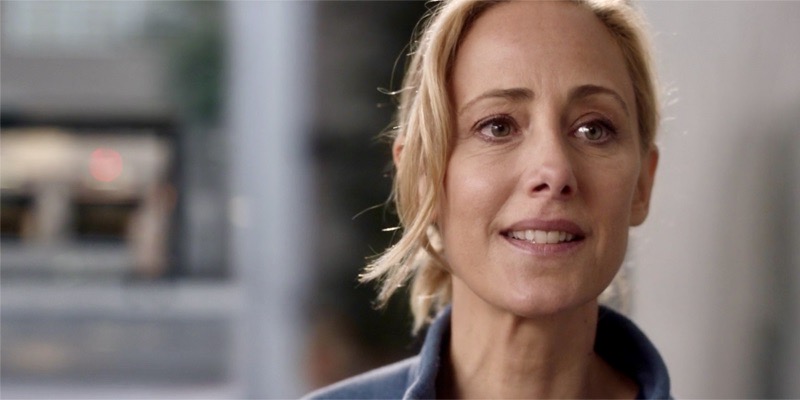 A close up still of Dr. Teddy Altman of Grey's Anatomy nervously smiling at the camera, eyes full of both fear and hope.