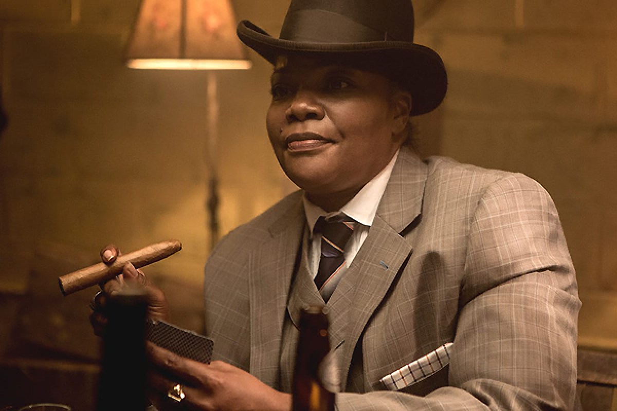 Mo'Nique in a three-piece suit and fedora, smoking a cigar, in Dee Rees' "Bessie" (2015). This depiction of one within a long history of showcasing Ma Rainey as a queer legend.