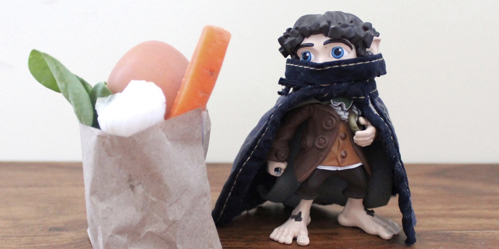 A feature image showing a toy Anti-Fascist wearing a face mask and cape near a bag of fresh produce.