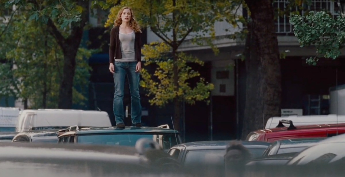 A scene from Imagine Me and You where Piper Perabo's character is stood on the roof of a car looking over traffic at a standstill in London