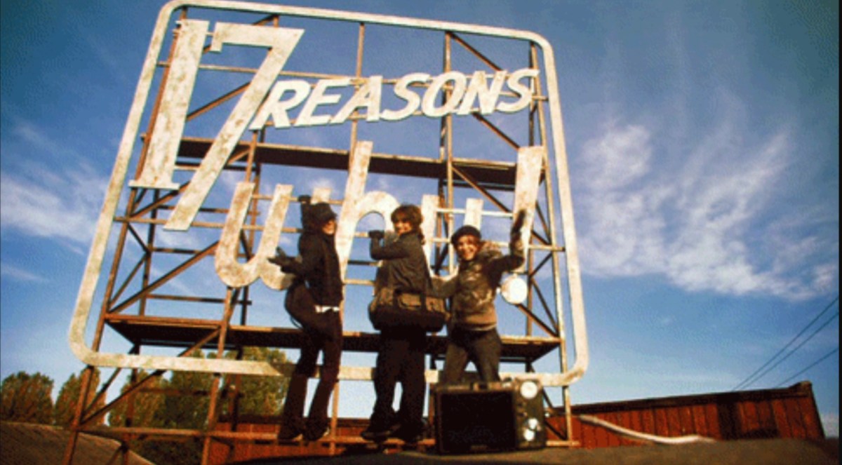 A scene from The L Word with Bette, Shane and Alice stood in front of a sign that says 17 Reasons Why