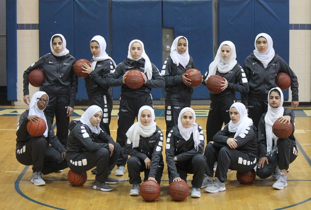 A class photo of a high school girl's basketball team, all wearing uniform and hijabs.